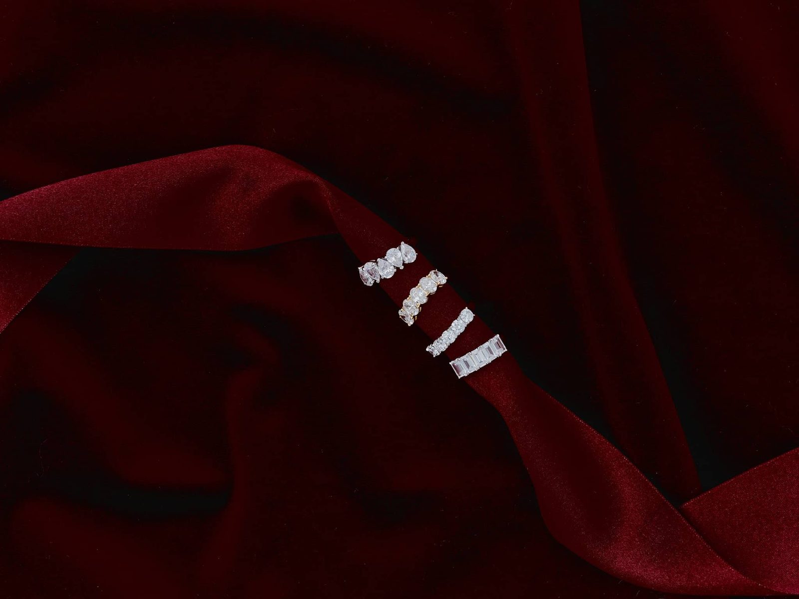 Four eternity bands resting on a ribbon of red velvet